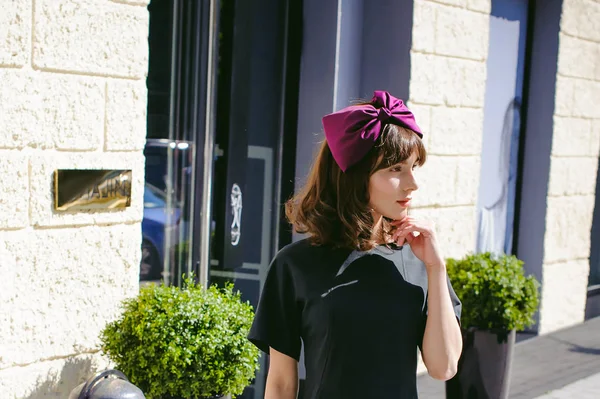 Karanlık bir şık elbiseli güzel kadın butikler yakınındaki cadde boyunca elini kolunu sallaya dönüyor. Bir moda kız portresi