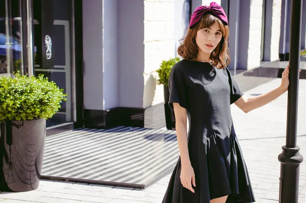 Karanlık bir şık elbiseli güzel kadın butikler yakınındaki cadde boyunca elini kolunu sallaya dönüyor. Bir moda kız portresi