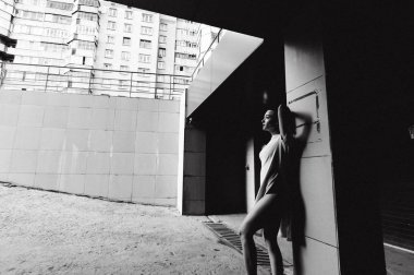 çıplak bacaklar beyaz spor ayakkabı ve cityscapes zemin karşı uzun bir T-shirt giymiş olan kadın