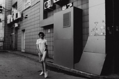 çıplak bacaklar beyaz spor ayakkabı ve cityscapes zemin karşı uzun bir T-shirt giymiş olan kadın