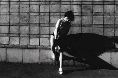 çıplak bacaklar beyaz spor ayakkabı ve cityscapes zemin karşı uzun bir T-shirt giymiş olan kadın