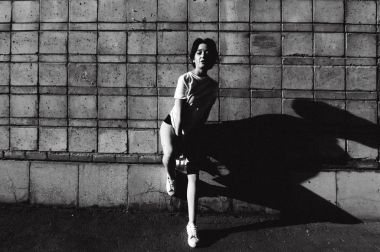 çıplak bacaklar beyaz spor ayakkabı ve cityscapes zemin karşı uzun bir T-shirt giymiş olan kadın