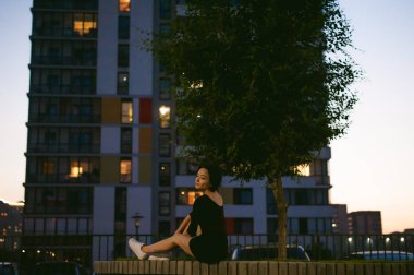 beyaz spor ayakkabı ve kentsel manzara fonunda siyah elbise giymiş güzel ayaklı genç kadın