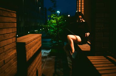 beyaz spor ayakkabı ve kentsel manzara fonunda siyah elbise giymiş güzel ayaklı genç kadın