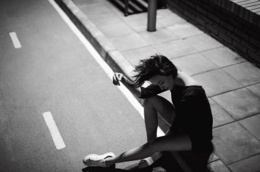 beyaz spor ayakkabı ve kentsel manzara fonunda siyah elbise giymiş güzel ayaklı genç kadın