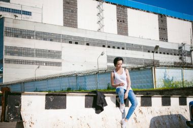 genç kadın beyaz spor ayakkabı, bir T-shirt ve cityscapes zemin karşı mavi kot pantolon giymiş. Sokak moda