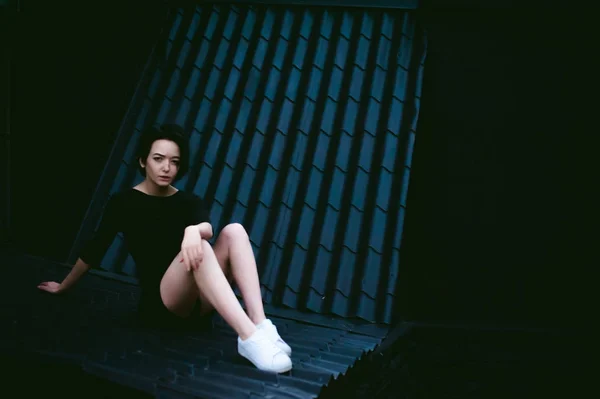 Jeune femme aux beaux pieds vêtue de baskets blanches et robe noire, sur fond de paysages urbains — Photo