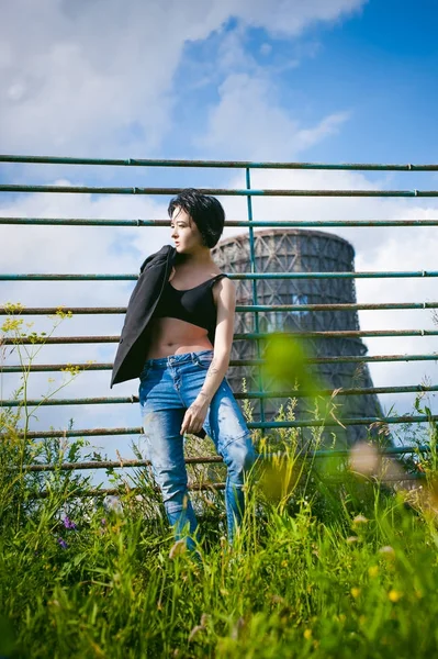 Mujer joven vestida con zapatillas blancas, top negro y jeans azules, sobre un fondo de paisajes urbanos. Moda callejera — Foto de Stock