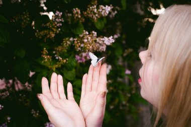 parmaklar beyaz kelebekler çiçek leylak ve yeşil yaprakların üzerinde tutun.