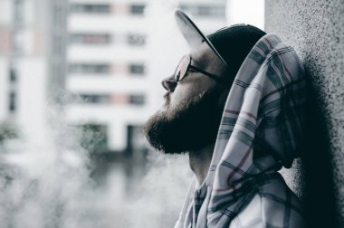 Kapüşonlu, açık renk ceketli, sakallı genç adam şehirde özgürce dolaşıyor.