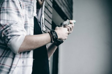 Kapüşonlu, kapüşonlu ve güneş gözlüklü sakallı genç adam şehirde serbestçe dolaşıyor ve bir e-sigara içiyor.