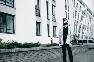 Kapüşonlu, açık renk ceketli, sakallı genç adam şehirde özgürce dolaşıyor.