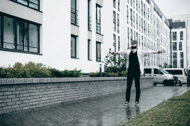 Kapüşonlu, açık renk ceketli, sakallı genç adam şehirde özgürce dolaşıyor.