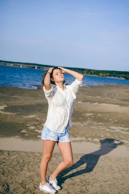 güzel bayanı kıvırcık saçlı, gençlik, romantik bir yolculuk bir kum plajındaki su ile sıcak yaz güneşli bir günde yürümek