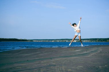 güzel bayanı kıvırcık saçlı, gençlik, romantik bir yolculuk bir kum plajındaki su ile sıcak yaz güneşli bir günde yürümek
