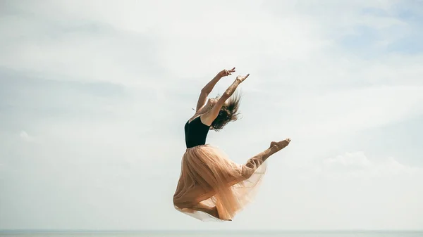 athletic woman stretching, jumping against the sky, a warm summer day, outdoor exercise