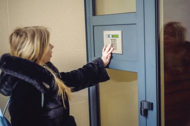 Genç sarışın kadın kürk ceket, doorphone panel kodu çeviren, evin içine girebilmen için parmaklarını ile düğmeleri presler