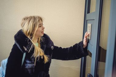 Genç sarışın kadın kürk ceket, doorphone panel kodu çeviren, evin içine girebilmen için parmaklarını ile düğmeleri presler