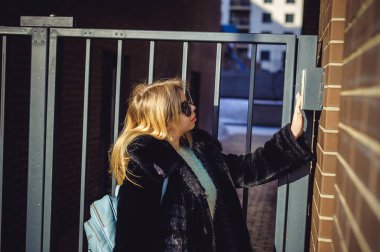 Genç sarışın kadın kürk ceket, doorphone panel kodu çeviren, evin içine girebilmen için parmaklarını ile düğmeleri presler