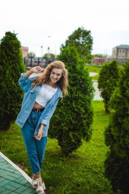 sokak kıvırcık paket fişi ile genç bir çekici duygusal kız portresi açık havada yürüyüş tarzı bir trendy mavi kot takım elbise giymiş. el pozisyonu