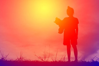 Siluet oyuncak ayı dağ ve gökyüzü günbatımı, mutlu kız tatil süreci tarzı vintage tonda bir kızla