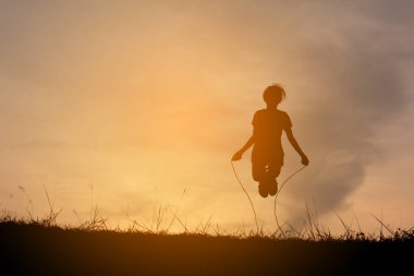 Siluet genç kız ip günbatımı üzerinde atlama. Zaman tatil mutlu ve eğlenceli, vintage sesi