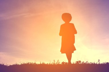 Gün batımında oynayan bir kız siluet 