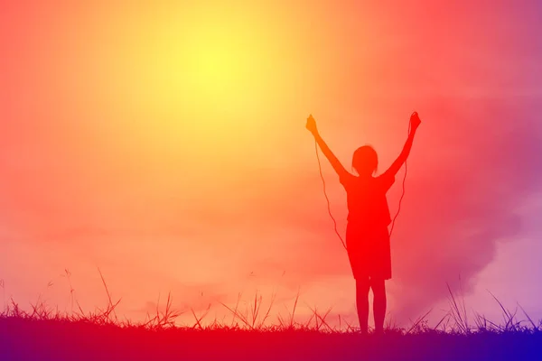 Silhouette ung flicka rep hoppande på solnedgången. Tid på semester glada och roliga, vintage ton — Stockfoto