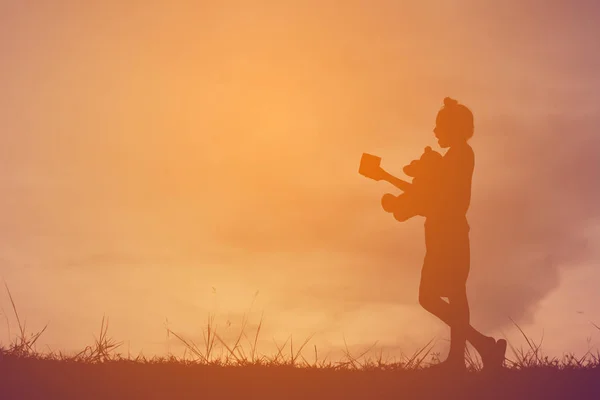 Silhouette una ragazza con orsacchiotto su montagna e cielo tramonto, ragazza felice in stile processo di vacanza tono vintage — Foto Stock