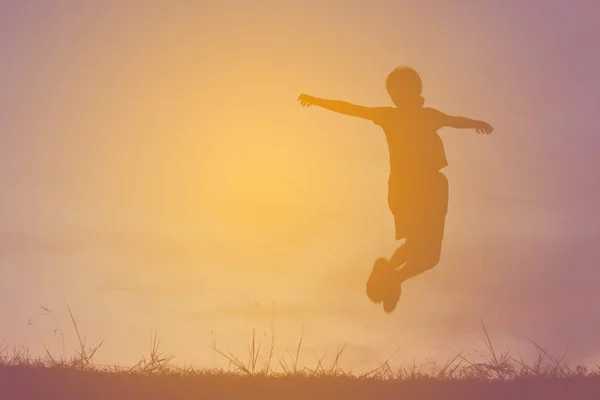 Silhouette ung flicka rep hoppande på solnedgången. Tid på semester glada och roliga, vintage ton — Stockfoto