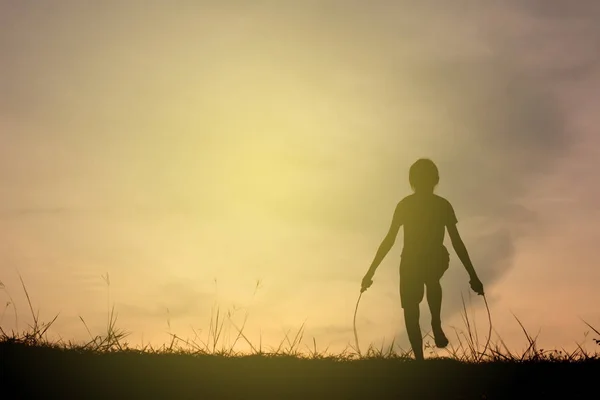 Silhouette giovane ragazza corda saltando sul tramonto. Tempo di vacanza allegro e divertente, tono vintage — Foto Stock