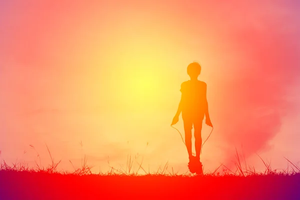 Silhouette giovane ragazza corda saltando sul tramonto. Tempo di vacanza allegro e divertente, tono vintage — Foto Stock