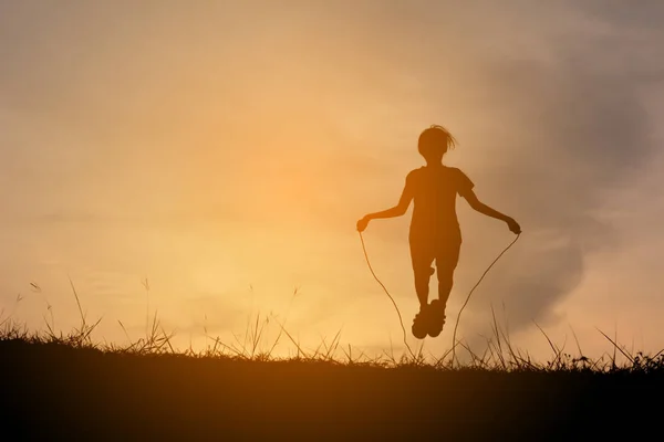 Silhueta menina corda pulando no pôr do sol. Tempo de férias feliz e divertido, tom vintage — Fotografia de Stock