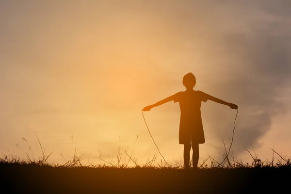 Silhouette giovane ragazza corda saltando sul tramonto. Tempo di vacanza allegro e divertente, tono vintage — Foto Stock