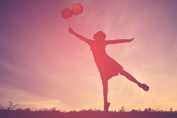 Silhouette en jente med ballong ved solnedgang – stockfoto