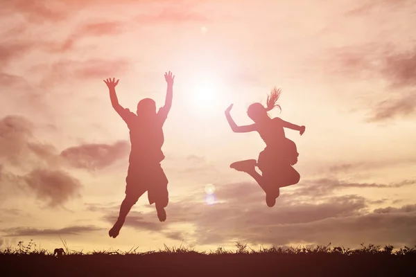 Silhueta crianças felizes dançando ao pôr do sol — Fotografia de Stock
