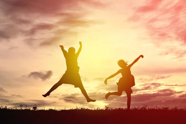 Silhueta crianças felizes dançando ao pôr do sol — Fotografia de Stock