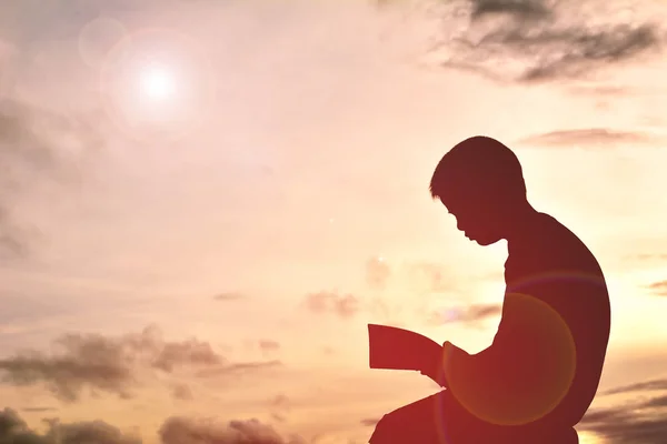 Egy fiú könyvével a sunset sziluett — Stock Fotó