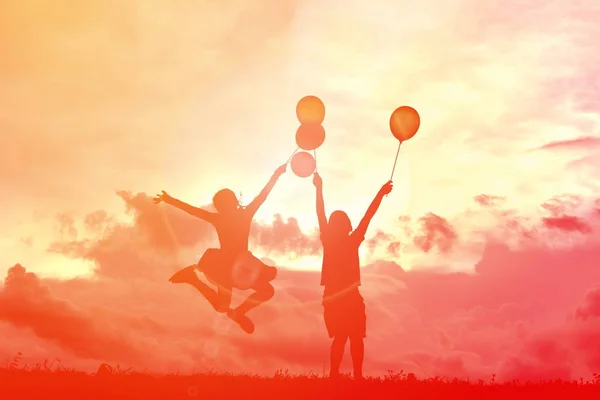 Silhouette Kinder mit Luftballon bei Sonnenuntergang — Stockfoto