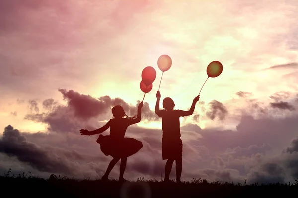 Silhouette enfants avec ballon au coucher du soleil — Photo