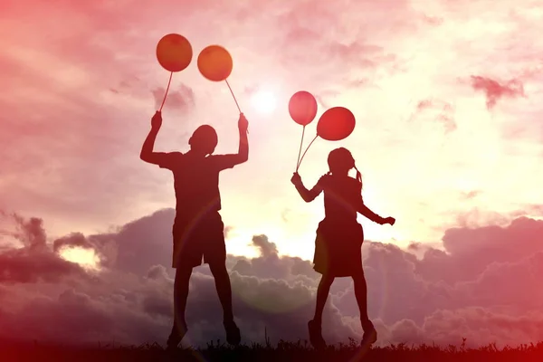 Silhouette Kinder mit Luftballon bei Sonnenuntergang — Stockfoto