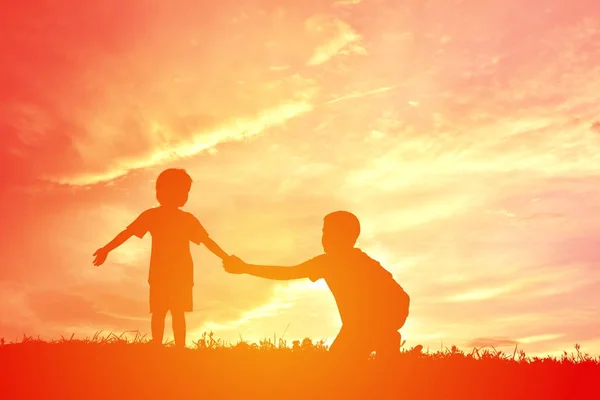 Sylwetka dzieci bawiące się na niebo zachód słońca — Zdjęcie stockowe
