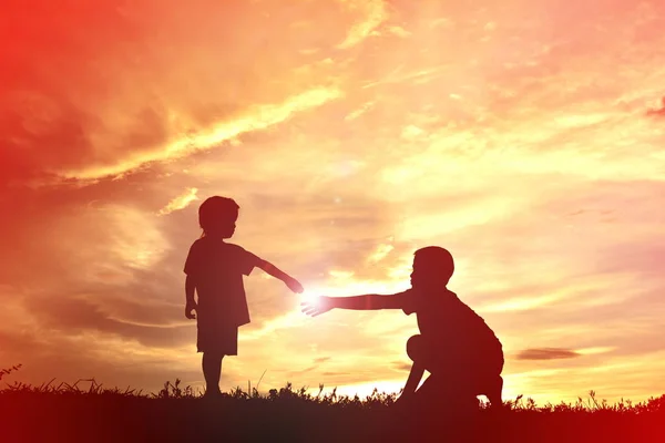 Silueta niños jugando en el cielo puesta de sol — Foto de Stock