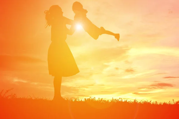 Silhouetten Mutter und kleine Tochter spielen bei Sonnenuntergang — Stockfoto