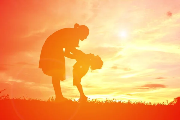 Silhouettes mère et petite fille jouant au coucher du soleil — Photo