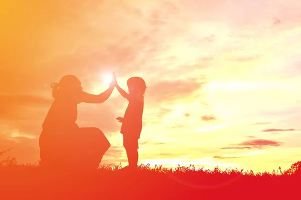 Silhuetas mãe e filha brincando ao pôr do sol — Fotografia de Stock