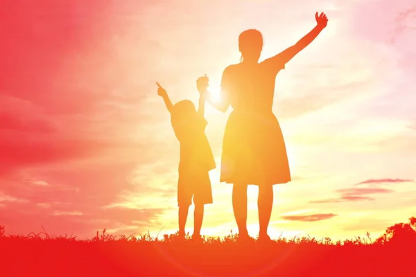 Silhouettes mother and little daughter playing at sunset — Stock Photo, Image