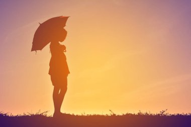 Günbatımı şemsiyesi olan siluet çocuklar