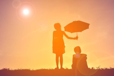 Günbatımı şemsiyesi olan siluet çocuklar