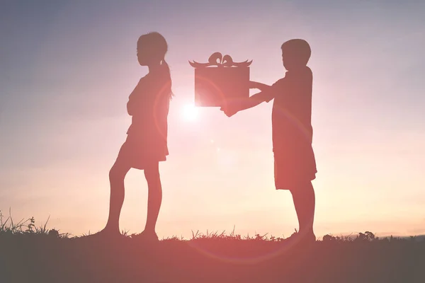 Silhouette Kinder mit Geschenk bei Sonnenuntergang — Stockfoto